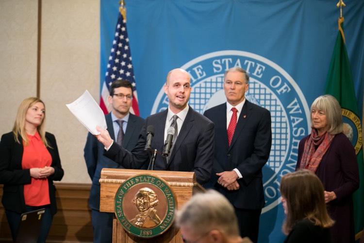 Washington State Rep. Drew Hansen holds a copy of the now-passed bill protecting net neutrality throughout the state.  He is joined by Gov. Jay Inslee, Rep. Norma Smith, and Sarah Bird, CEO of MOZ.